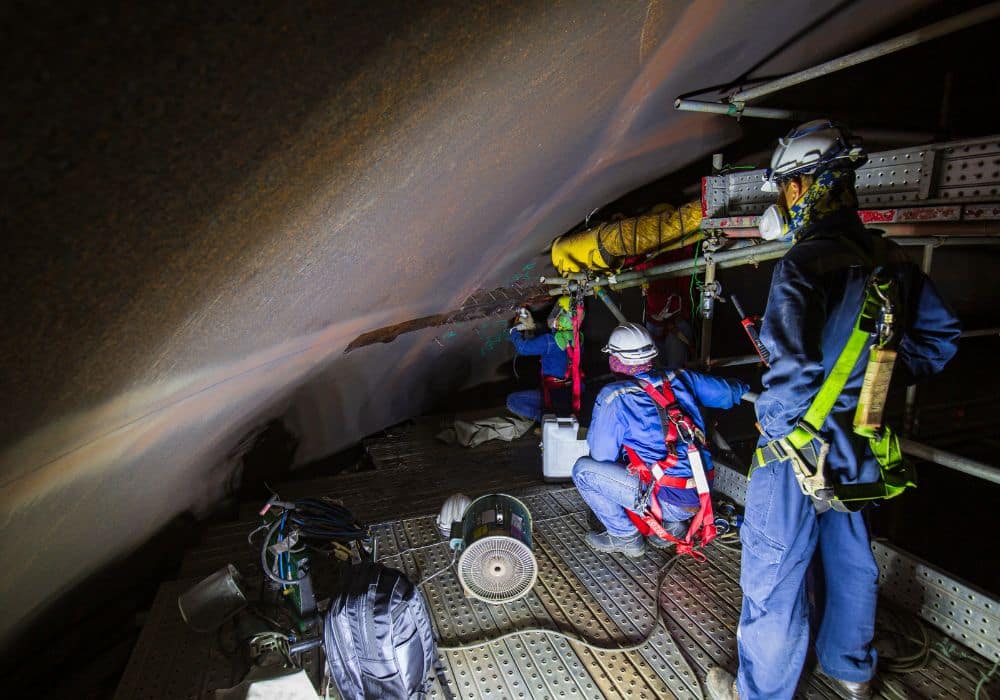industrial workers wearing PPE in a confined space ; confined space cleaning